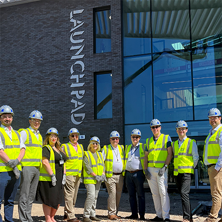 "Group shot of people in High vis and hard hats standing outside the Launchpad.