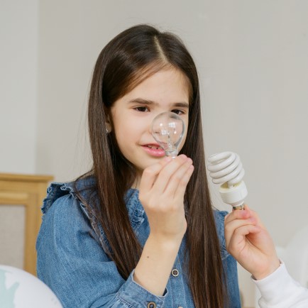 Young girl holding a lightbulb and looking at it.